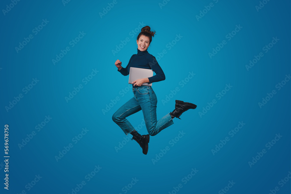 Obraz premium Full length body size of excited positive woman wearing jeans holding notebook going conference isolated on blue color background. Modern lifestyle. Blue