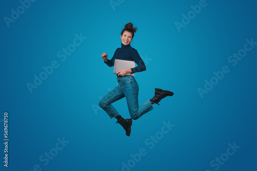 Full length body size of excited positive woman wearing jeans holding notebook going conference isolated on blue color background. Modern lifestyle. Blue