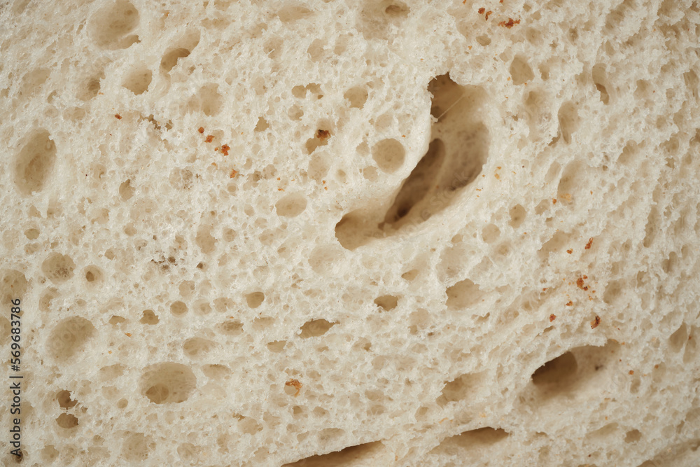 Natural background from a piece of white wheat bread. Close-up. Space for lettering and design.