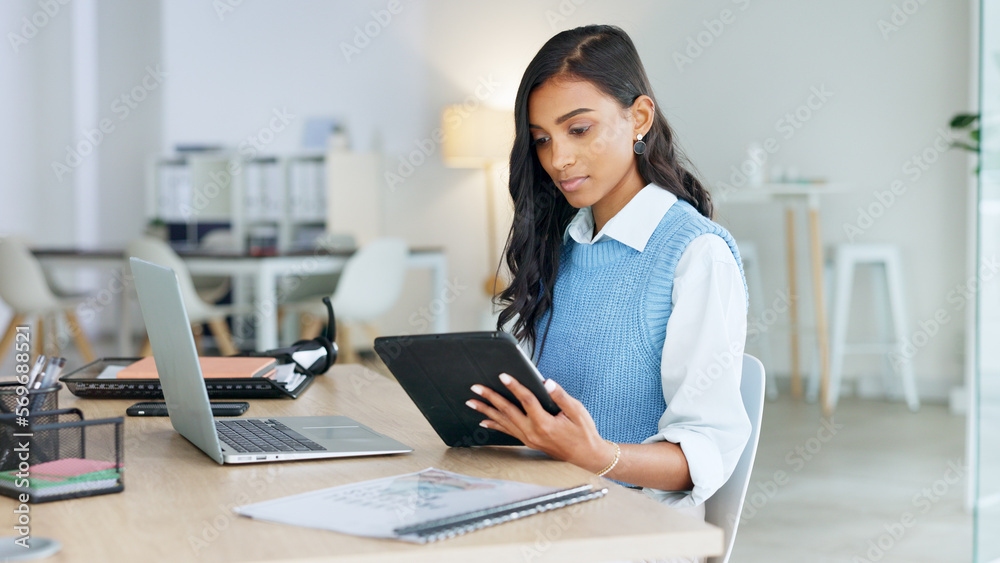 Trendy marketing professional using an online app to network, meet deadlines and stay connected during office hours. Young business woman using her laptop and tablet while working in the office. Trendy marketing professional using an online app to network, meet deadlines and stay connected during office hours. Young business woman using her laptop and tablet while working in the office.