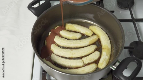 Pour the cocoa chocolate mixture into the hot pan with fried bananas to make the cake. High quality 4k footage