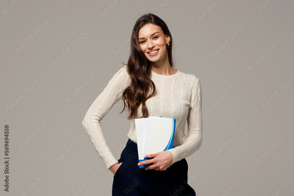 Φωτογραφία Stylish young girl with long hair and glowing skin is holding cosmetic products in her hands and smiling