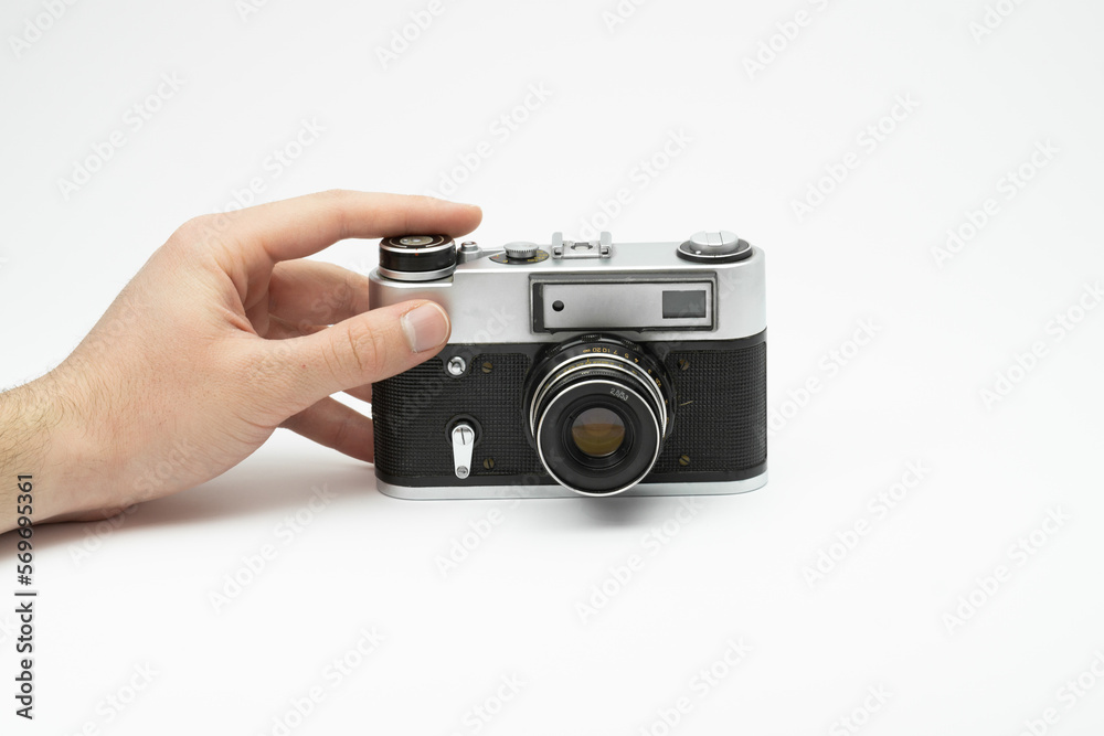 Fototapeta premium Hand pressing the shoot button on a vintage film camera isolated on white backgorund. Hand taking picture with an old film camera. Finger pressing the shoot button on a film camera 