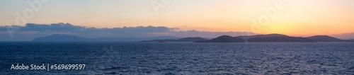 Rocky Island on Mediterranean Sea. Rinia near Mikonos, Greece, Europe. Nature Background Panorama. Sunrise Sky