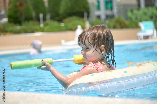 Small child joyfully splashing water in the pool in summer