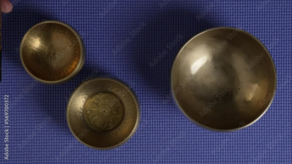 sound healing with a set of Tibetan singing bowls, top view with a mallet and hand of a senior male