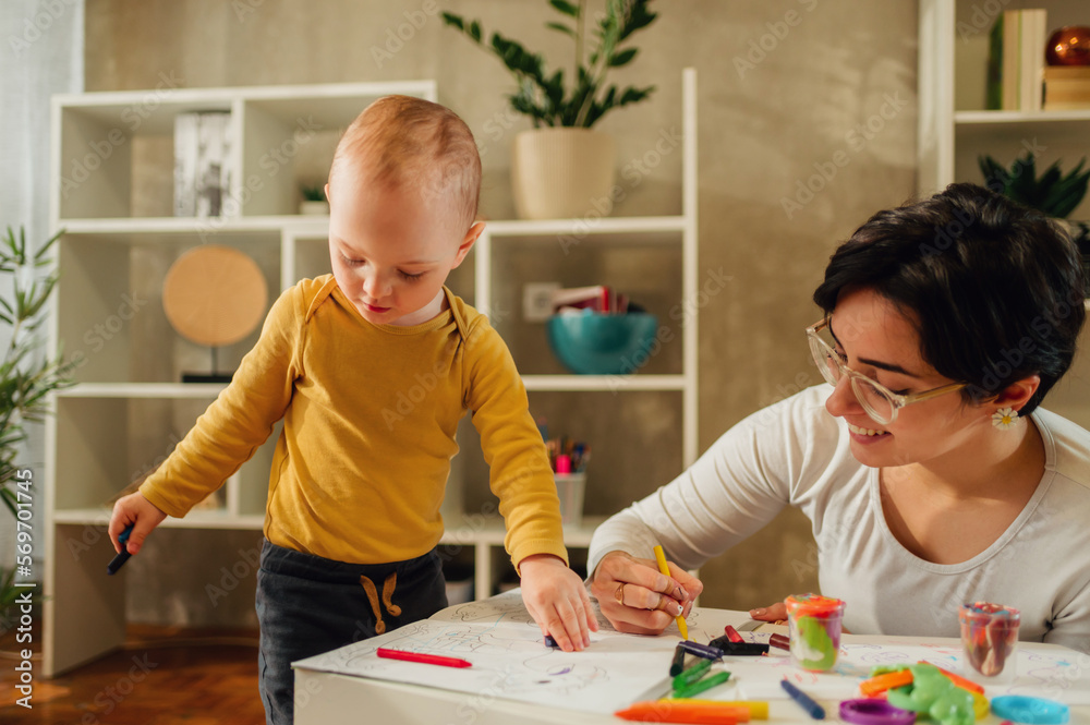 Mother and son drawing with crayons at home and having education Mother and son drawing with crayons at home and having education