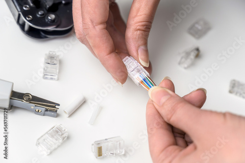 A woman's hand inserts an internet cable into a clamp connector. utp ethernet network cable plug. The concept of internet communications. photo
