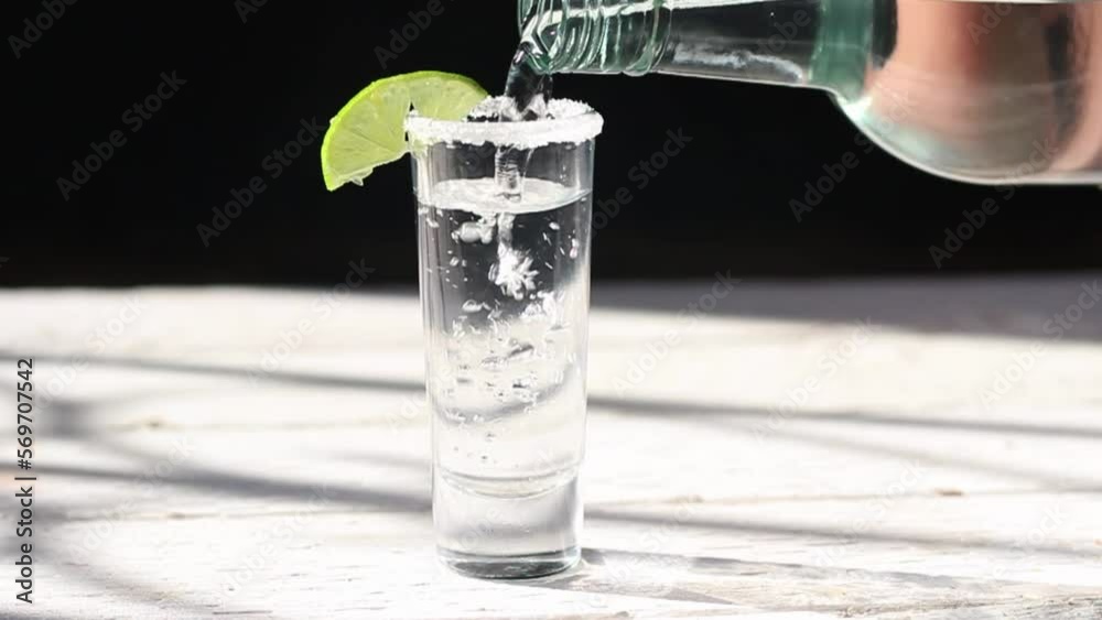 close up slow motion of bottle serving shot of tequila, mezcal