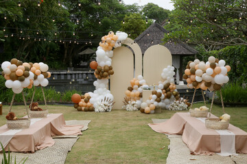 Creative gender neutral baby shower or birthday decoration in the garden. Bohemian style outdoor event set up with balloons. White cream peach caramel balloon arch kit.