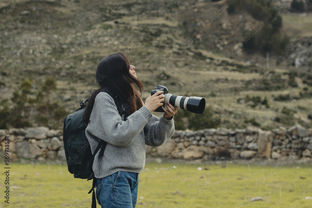 Woman photographer taking pictures with her camera in a part of the Andes mountain range in Peru. Concept professions, people, travels and vacations. Woman photographer taking pictures with her camera in a part of the Andes mountain range in Peru. Concept professions, people, travels and vacations.