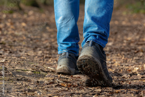 Hiking concept, Selective focus of a man legs with blue jean and shoes in the move, Low angle of people walk in the forest with nature path, Hobby, Leisure activities, Sport and recreation background.