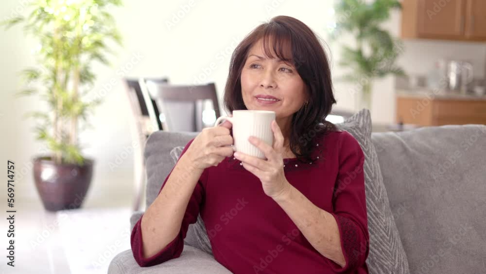 Beautiful asian woman relaxing drinking coffee sitting on comfortable couch in leisure home living room bokeh furniture background Beautiful asian woman relaxing drinking coffee sitting on comfortable couch in leisure home living room bokeh furniture background