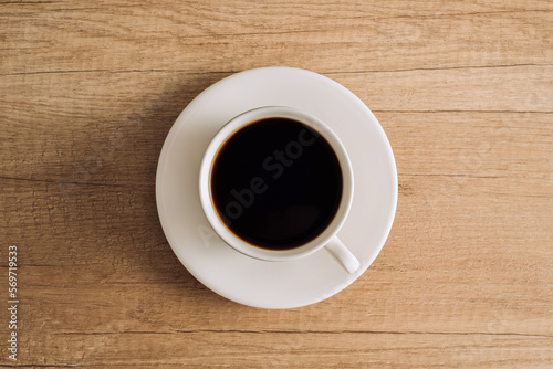 Flat lay black coffee in a white cup with a saucer on a wooden table