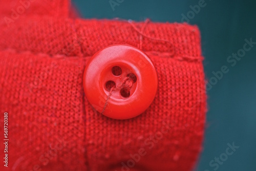 piece of clothing made of red fabric and one small plastic button