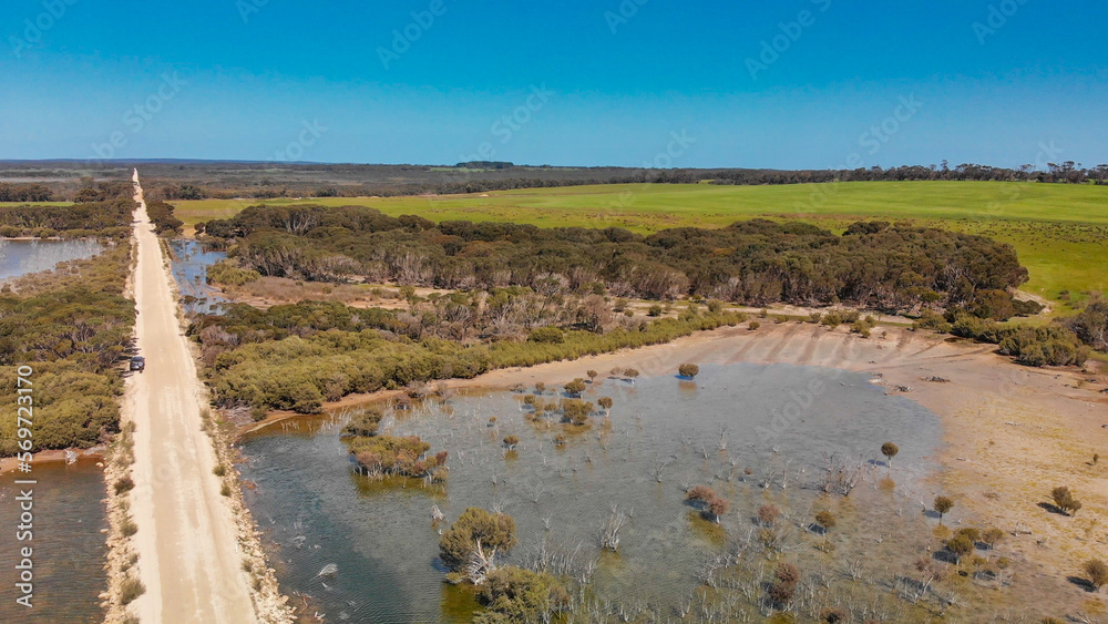Kangaroo Island unpaved road along lake and trees, aerial view from drone - Australia