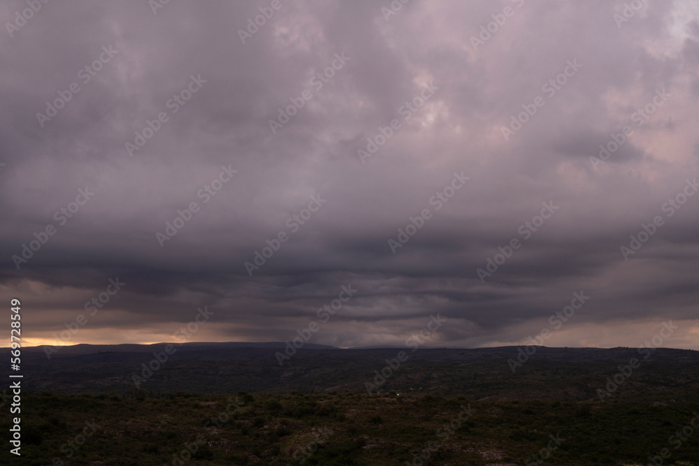 Dramatic cloudscape. Panorama view of the hills and field under a cloudy sky, at dusk.