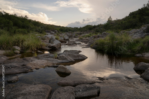 View of the river across the rocky hills at sunset. The sky reflection in the water surface. photo