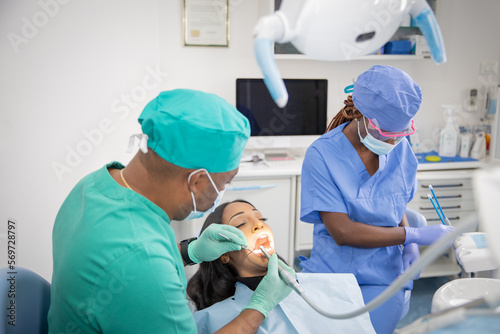 An African dentist checks the oral health of his patient while his assistant prepares the work tools
