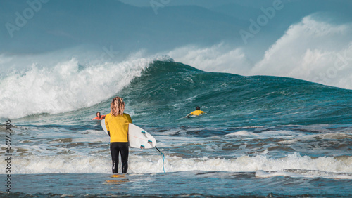 Canvas Print A pro surfer on his back with a surfboard  standing in front of the sea looking