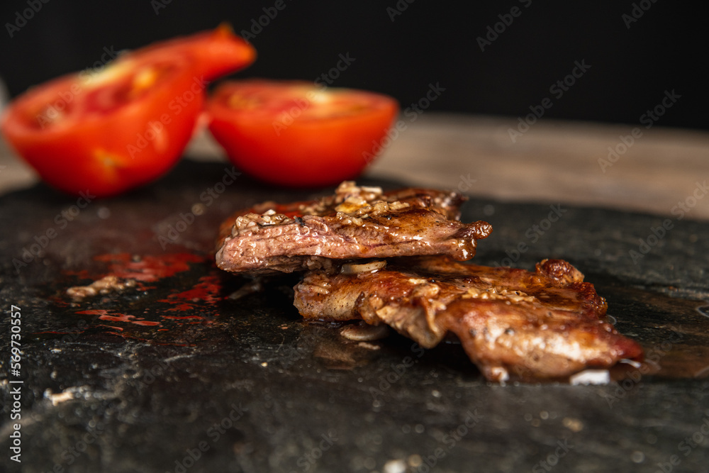 Entraña carne asada con tomate sobre base oscura 