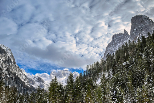 Dense clouds above the Dachstein peak and the surrounding Alpine ranges with pine forest in the foreground 