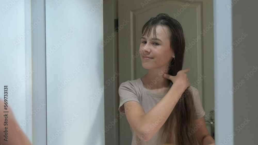 Teenage girl combing her hair. A beautiful girl combs her long hair while looking at her reflection in the mirror. Teenage girl combing her hair. A beautiful girl combs her long hair while looking at her reflection in the mirror.