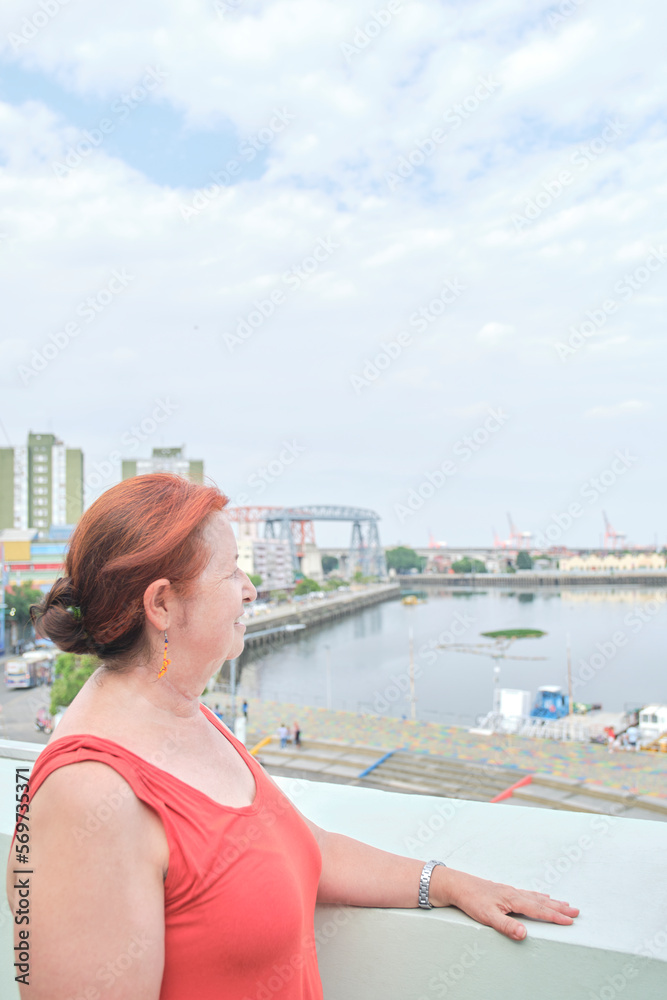 Portrait of happy mature hispanic woman enjoying the view in the tourist neighborhood of La Boca, in Buenos Aires, Argentina, on a sunny summer day.