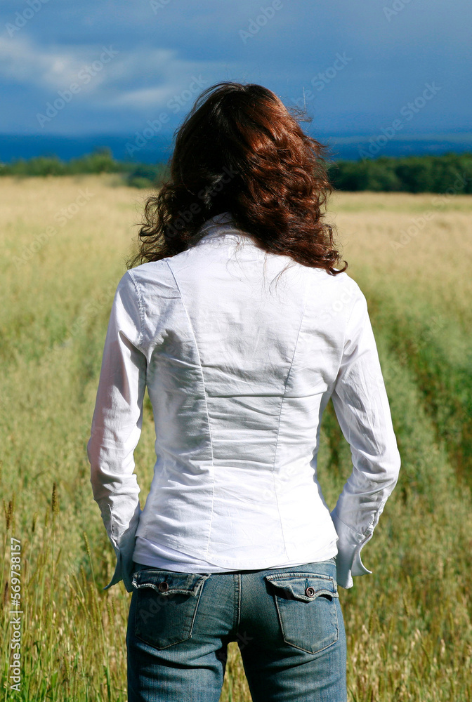 Rear view of young woman overlooking farmland in summer. Rear view of young woman overlooking farmland in summer.