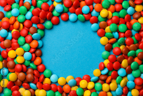 Frame of tasty colorful candies on blue background, flat lay. Space for text © New Africa