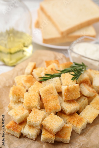 Delicious crispy croutons with rosemary on table, closeup