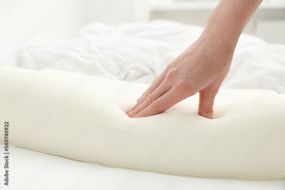 Woman touching orthopedic memory foam pillow on bed, closeup. Space for text Woman touching orthopedic memory foam pillow on bed, closeup. Space for text
