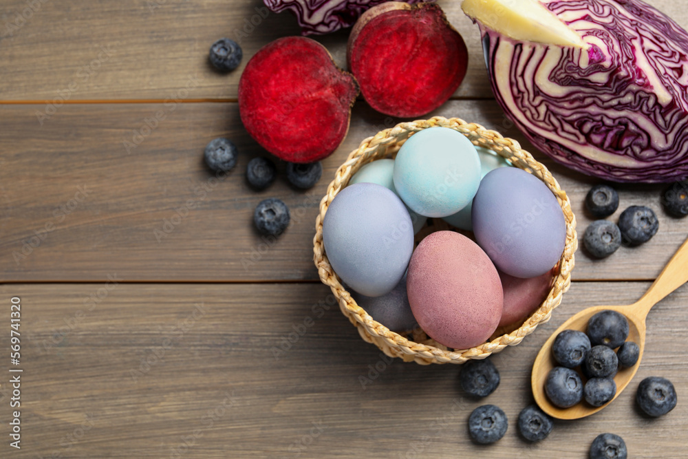 Colorful Easter eggs painted with natural dyes and ingredients on wooden table, above view