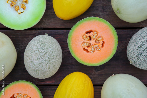 Different types of tasty ripe melons on wooden table, flat lay