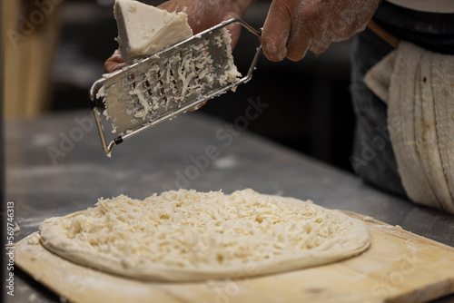 Φωτογραφία Close up of the making process, male hands rubbed cheese grated