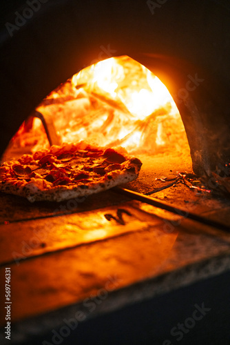 Pizza in the traditional pizza oven with a wood fire. Close up of hot cooking.