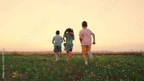 Happy childhood. Teenagers play running. Funny children play in park, friends run in summer. Child run on grass, sunset. Happy boy, girl run in field, playing in nature. Family, weekend outdoors. photo