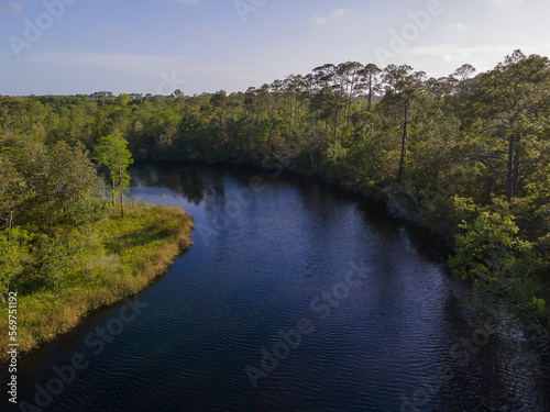 Curved river waterway through the forest at Navarre, Florida. River running in the middle of a forest with green trees and a background of clear sky.