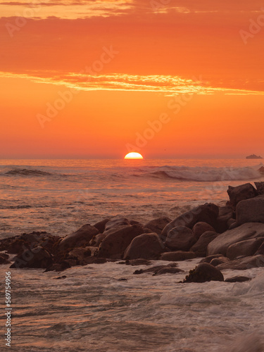Sunset at El silencio beach, Lima, Peru. Golden hour, the sun setting on the horizon and the ocean breaking on the rocky shore. © Prock86