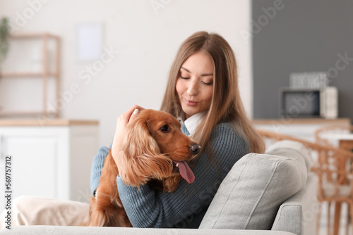 Young woman with red cocker spaniel sitting on sofa in kitchen