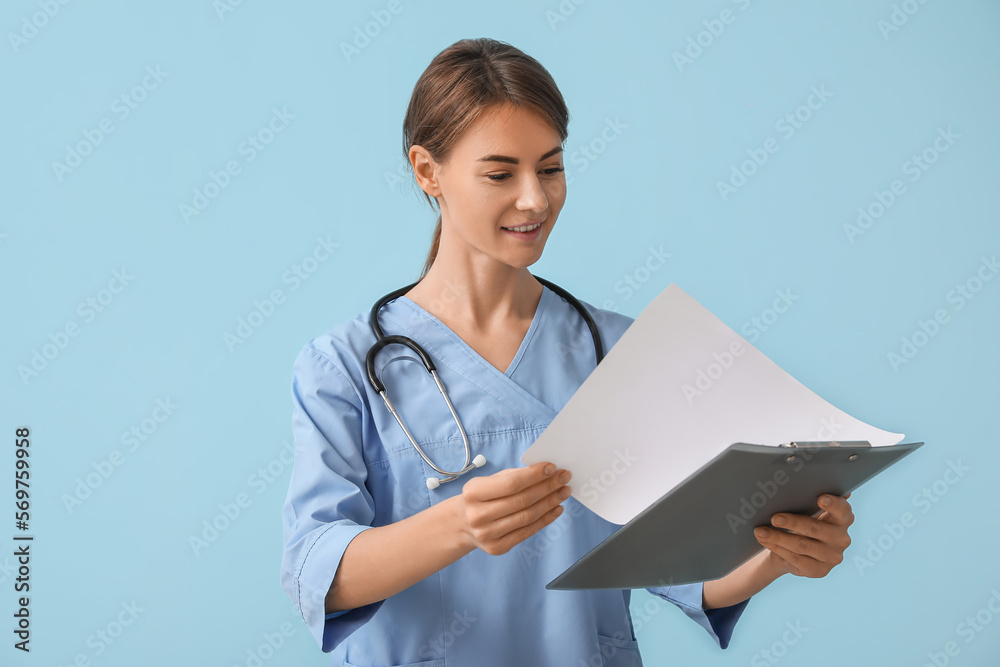Female medical intern with clipboard on blue background Female medical intern with clipboard on blue background
