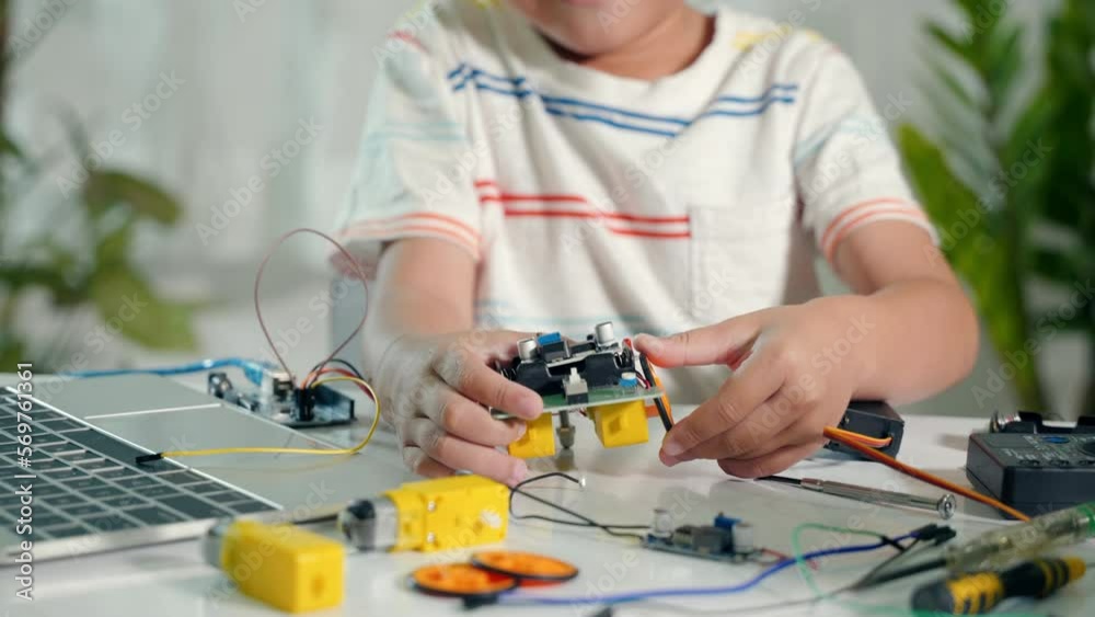 Asian kid boy assembling wheel into Arduino robot car homework, Little ...