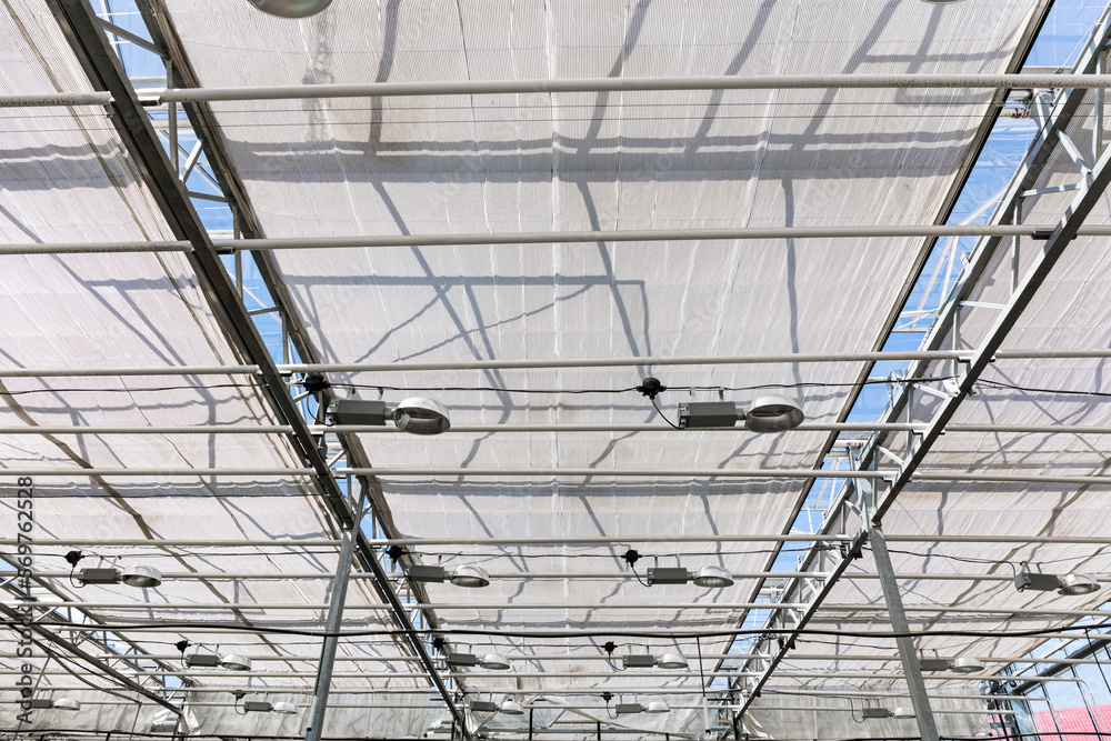 greenhouse interior with grow-light installation under glass roof greenhouse interior with grow-light installation under glass roof