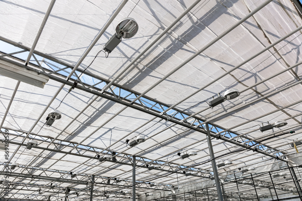 glass roof of modern greenhouse with lamps for lighting plants