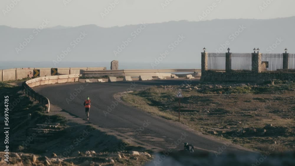 Runner running empty road, long telephoto lens back static view Runner running empty road, long telephoto lens back static view