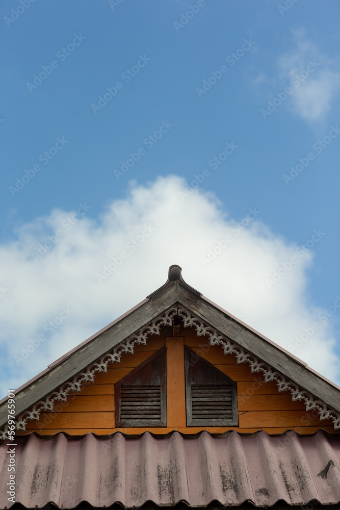 The roof of the house is carved on the wood with beautiful patterns. On a cloudy sky day