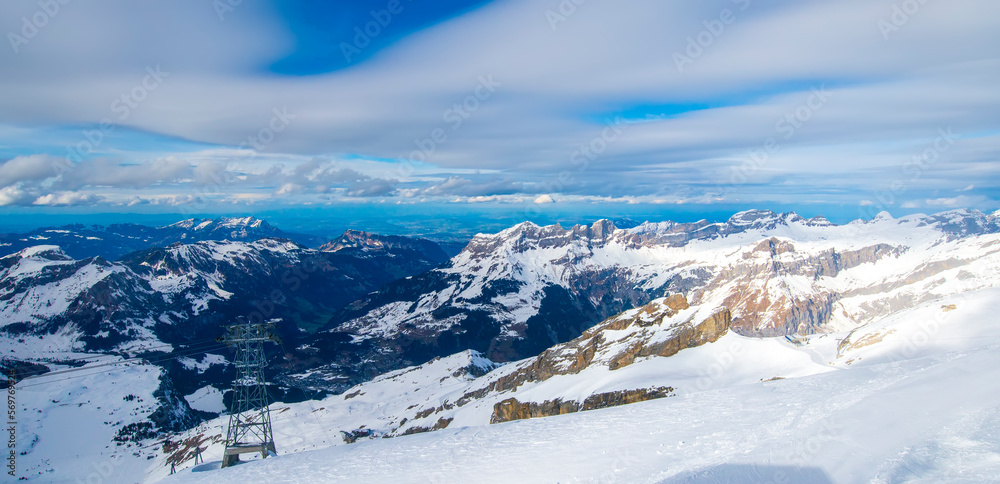 Panorama winter landscape of mountains in Switzerland.Snow mountain with a ski slope in the winter season.Summit of Titlis mountain with snow coverage on a sunny day.