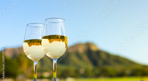 Pair of wine glasses against a beautiful tropical Diamond head in Hawaii mountain background. Dream summer romantic honeymoon vacation Hawaii concept. 