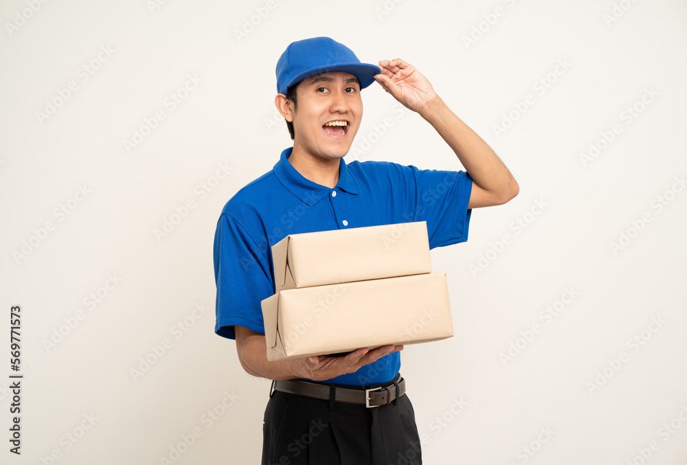 Happy delivery asian man in blue uniform standing holding box parcel cardboard on isolated white background. Smiling male service worker. Delivery courier and shipping service. Happy delivery asian man in blue uniform standing holding box parcel cardboard on isolated white background. Smiling male service worker. Delivery courier and shipping service.