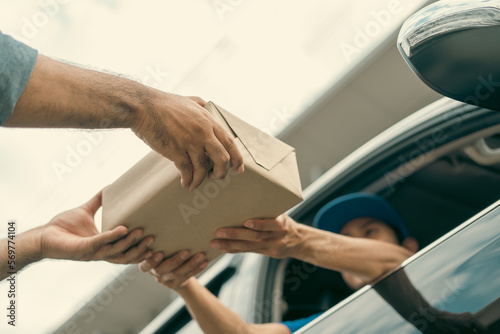Asian delivery man with parcel in hand of blue uniform sending parcel to customer Sticking his head outta the windshield from shopping online service. Courier man send a package to destination.